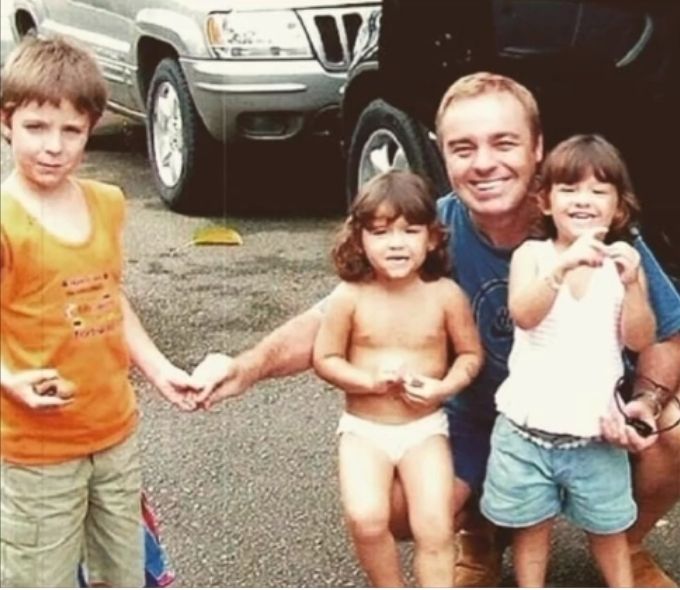 filha-gugu-liberato-posta-foto-irmãos-pai-dia-das-crianças foto antiga de gugu liberato com seus três filhos. ele está agachado abraçando sofia e marina, e dando a mão para João Augusto