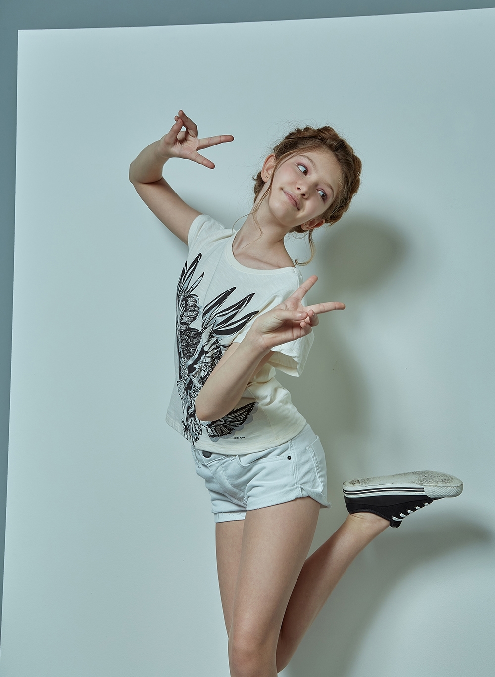 Menina posa com a perna para cima e olhando para tr&aacute;s vestindo camiseta e shorts