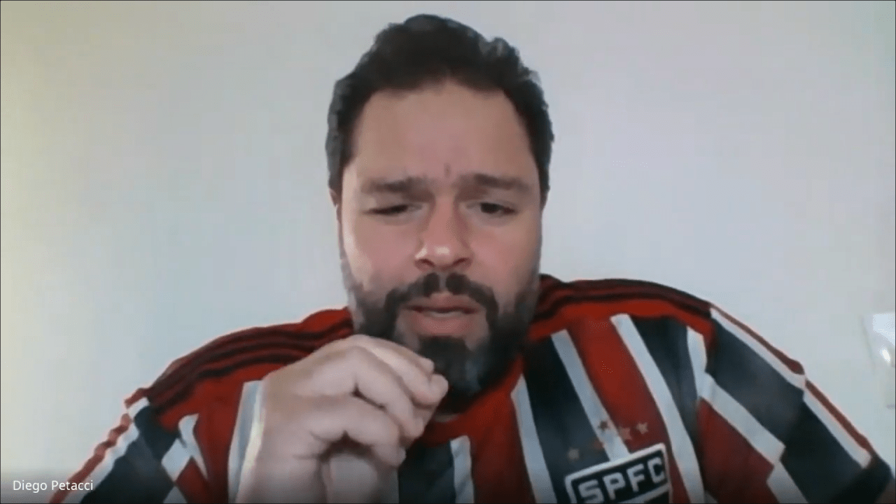 Homem com cabelo preto e barba vestindo camisa do São Paulo Futebol Clube e gesticulando