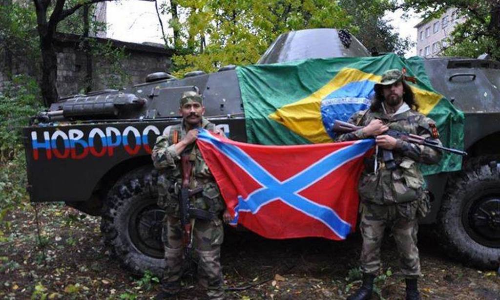 Rafael Lusvarghi Imagem mostra Rafael, à direita, ao lado de um guerrilheiro e à frente de um tanque de guerra