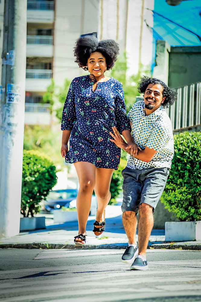 São Paulo 10 dezembro 2021Lucas e RuthFoto Alexandre Battibugli VSP Um casal posa atravessando uma rua. Ela está saltando do chão e ele a ajuda a se manter no ar com as mãos na cintura dela