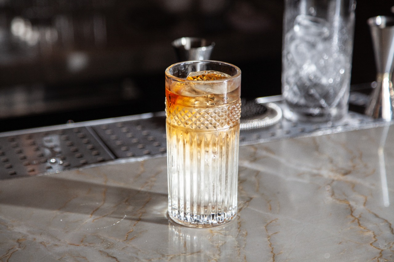 Drinque bicolor servido em copo de fundo redondo