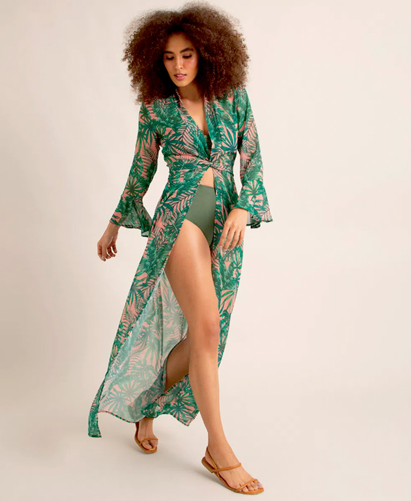 saida de praia.png Uma mulher negra posa com uma saída de praia verde, grande e florida