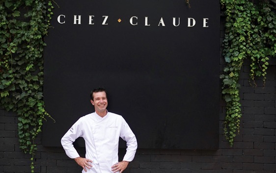 Chef posa em frente da fachada do restaurante