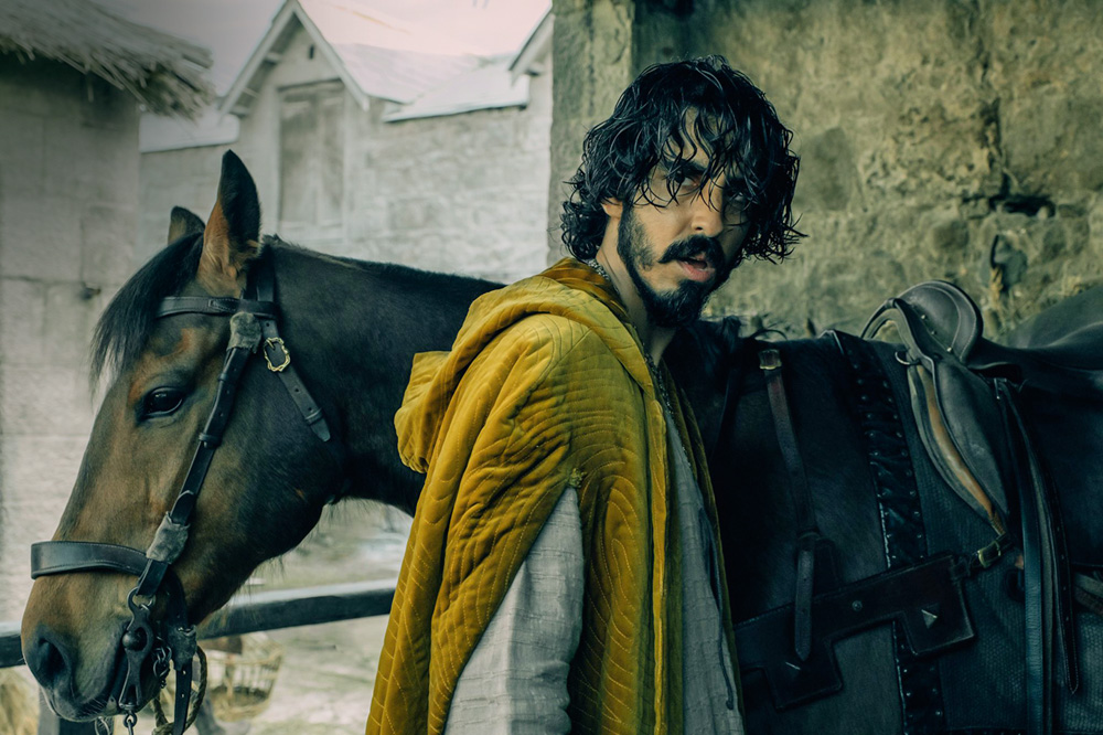 Imagem mostra homem com cabelo molhado e roupa amarela em frente a um cavalo.