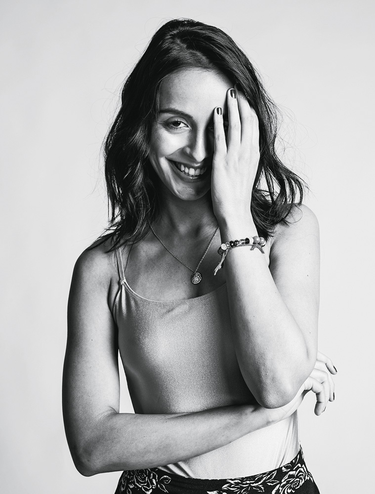 Aline Bei_crédito Lorena Dini.jpg Imagem em preto e branco mostra mulher sorrindo com uma das mãos sobre o rosto.