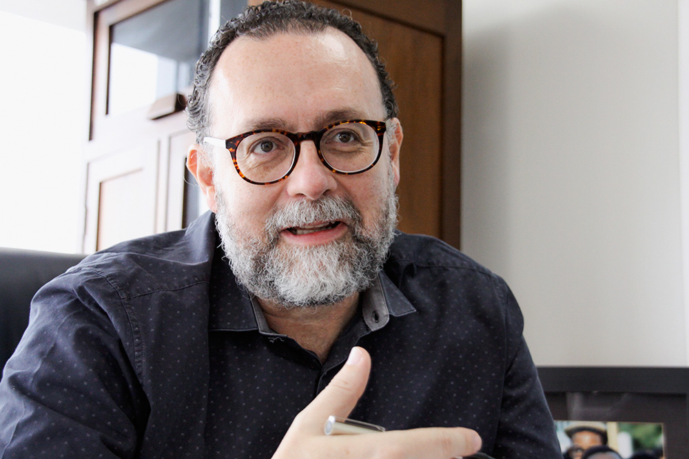 FOTO_IMG_0420.JPG Foto de Carlos Bezerra Jr. Ele é um homem branco, calvo, de barba branca. Usa óculos e uma camisa preta.