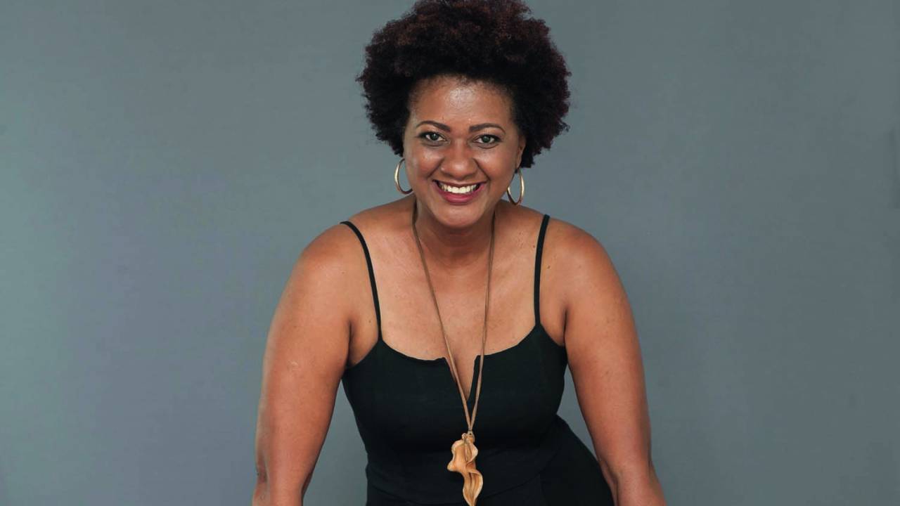 Imagem mostra mulher de vestido preto com colar dourado.