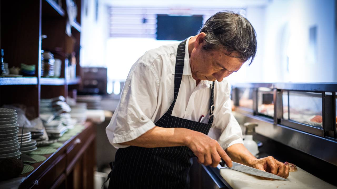 Imagem de Masanobu Haraguchi cortando alimento na tábua