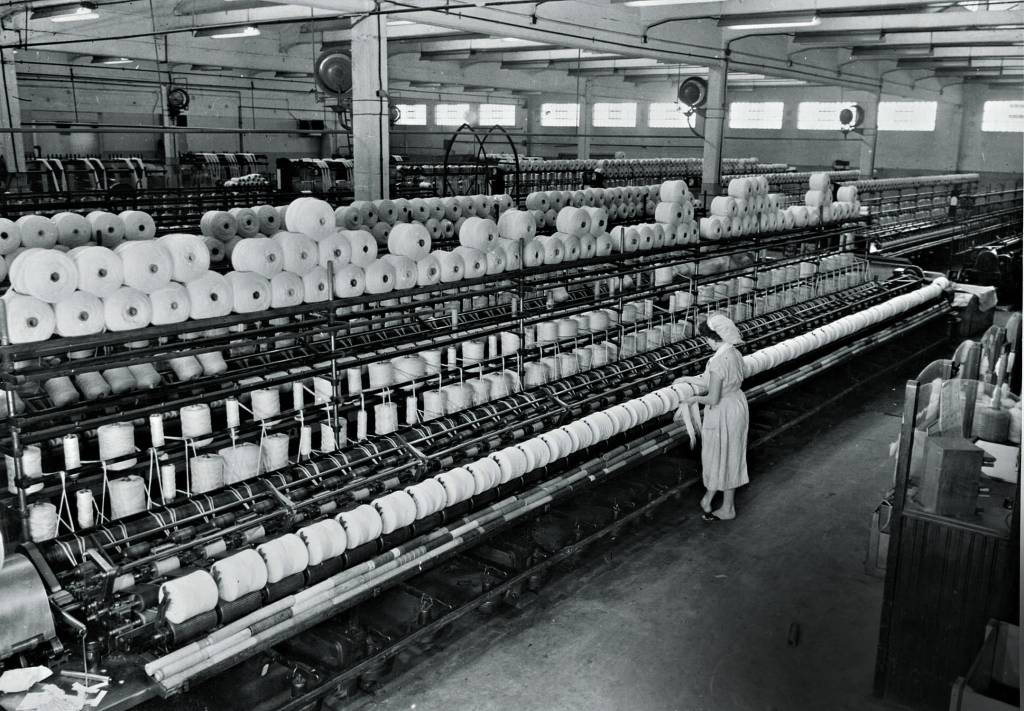 Vista interna do lanifício da fábrica da S.A. Moinho Santista no bairro do Belenzinho. Brasil, São Paulo, São Paulo_ 1954_ Autoria Ernesto Mandowsky..jpg Imagem mostra mulher trabalhando em linha com diversos rolos de lã.