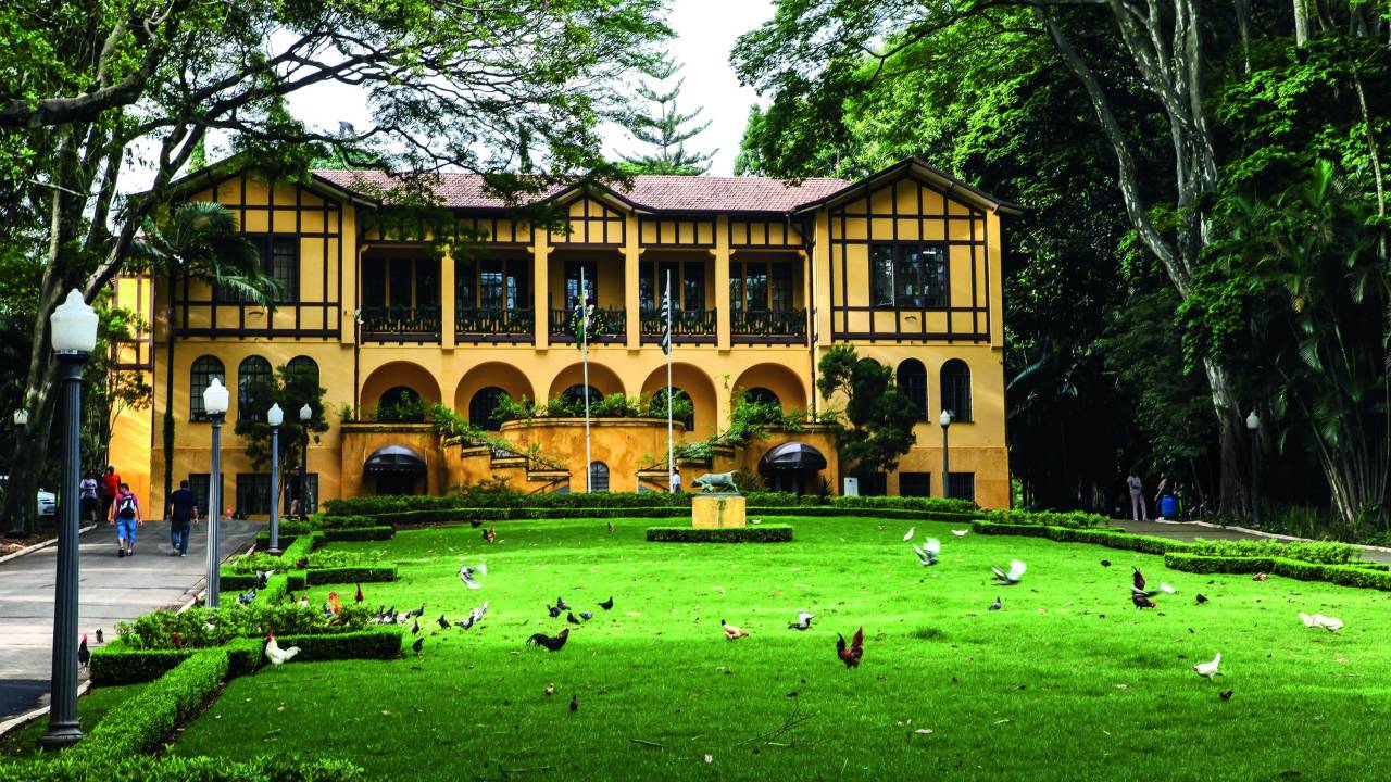 Imagem mostra casa amarela em frente a gramado.