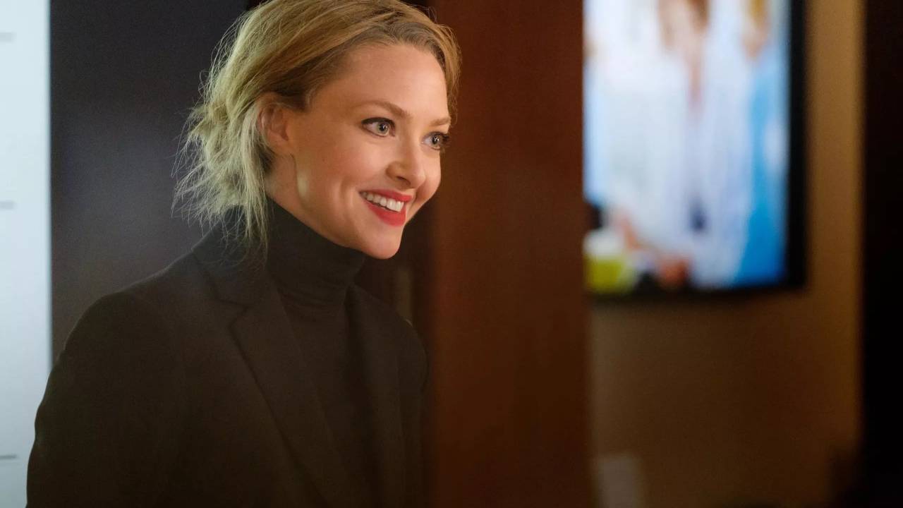 AmandaSeyfried, com roupa preta e batom vermelho, sorri
