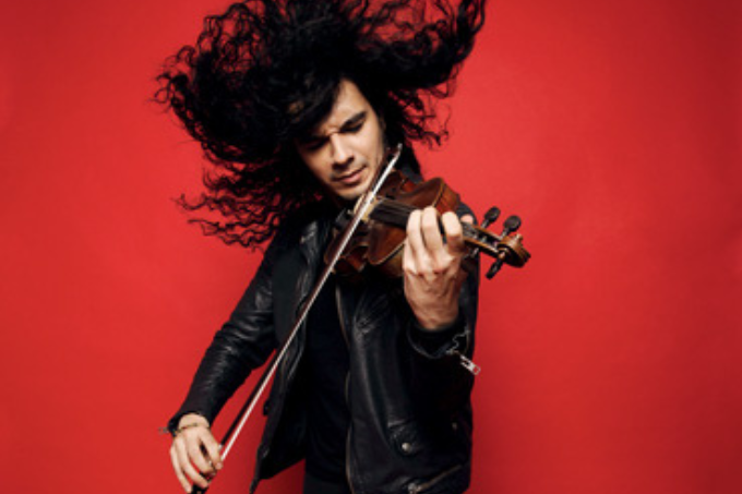 Imagem mostra homem de cabelo comprido tocando violino sobre fundo vermelho