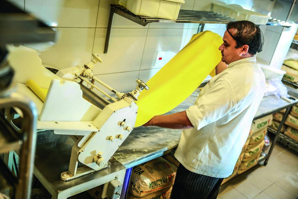 DEVORO_3.JPG Imagem mostra cozinheiro colocando massa em aparelho culinário