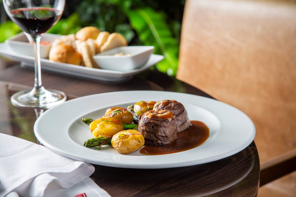 Loup Dois medalhões de carne complementados por batatas, aspargos e molho servidos em prato raso de cor branca