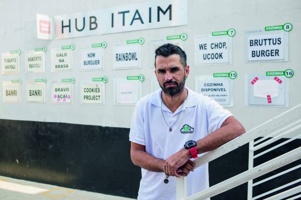 EDITADAS VEJA SP15.jpg Imagem mostra homem de camiseta branca apoiado sobre corrimão. Ao fundo, parede com placas com nomes de restaurantes.