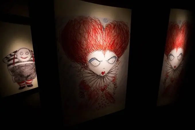 Exposição baseada no universo fantástico de Tim Burton. Divulgação Foto exibe quadro de figura monstruosa de olhos brancos e cabelo vermelho em formato de coração.