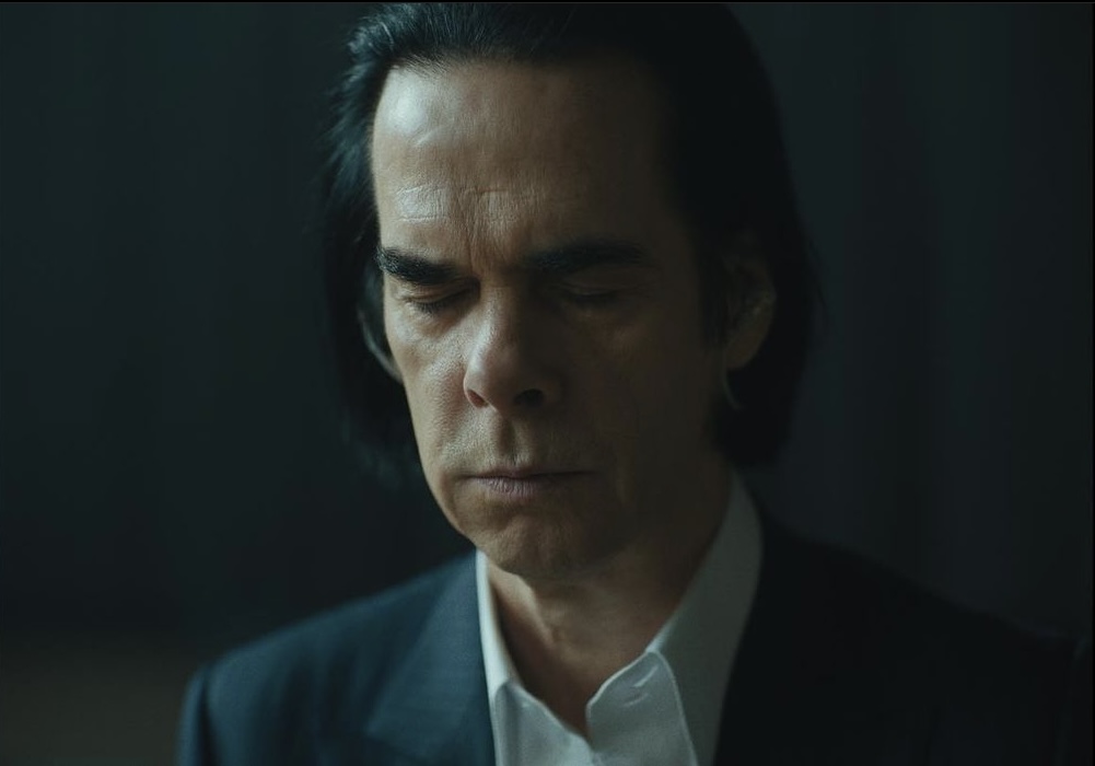Imagem mostra homem de cabelo preto escuro vestindo terno e camisa branca. Ele está de olhos fechados.