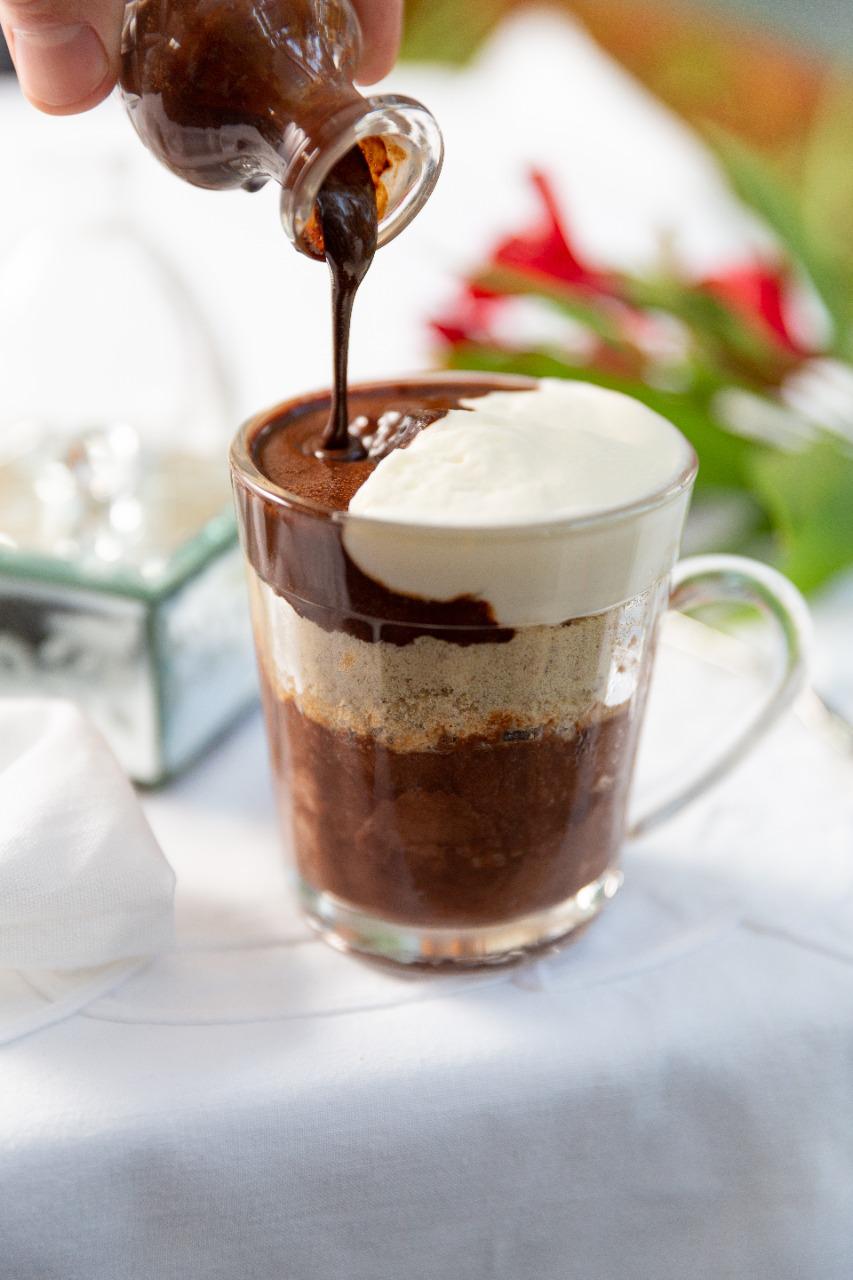 Farabbud Sobremesa servida em caneca de vidro, repleta de chocolate, farofa e creme de cor branca