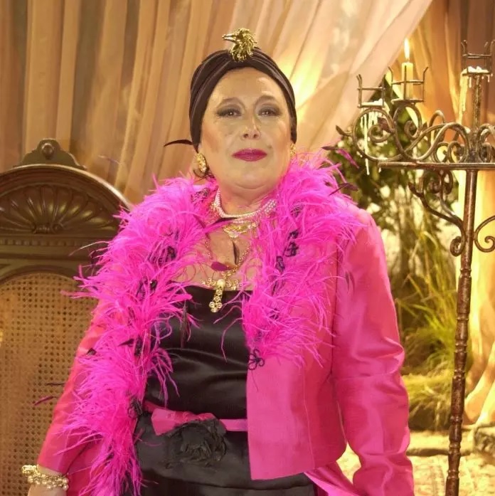 Marilu Bueno posando com roupa rosa pink e turbante preto.