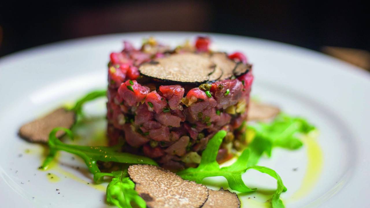 Steak tartare, com filé-mignon em cubos temperados com azeite, sal, pimenta-do-reino, alcachofra, alcaparra, cebola picada, toque de alho, suco de limão-siciliano e pasta de trufas.