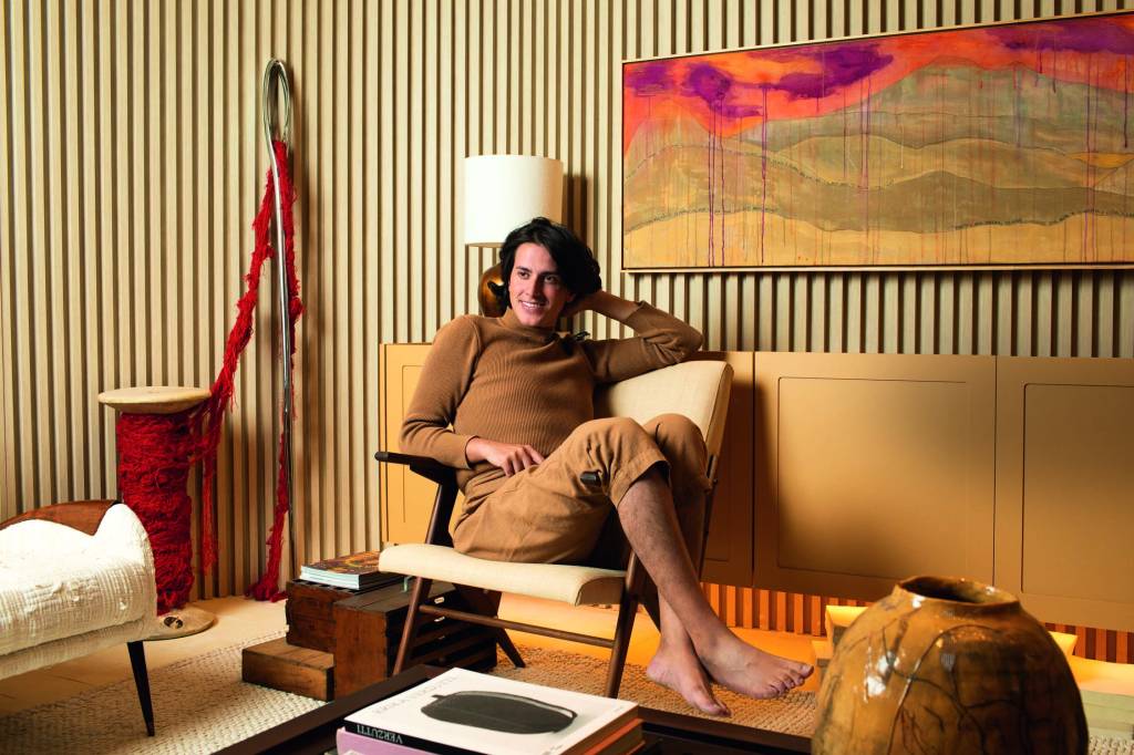 CASACOR 2022 Imagem mostra pessoa com roupas bege sentada em poltrona, em ambiente também bege e amarelo