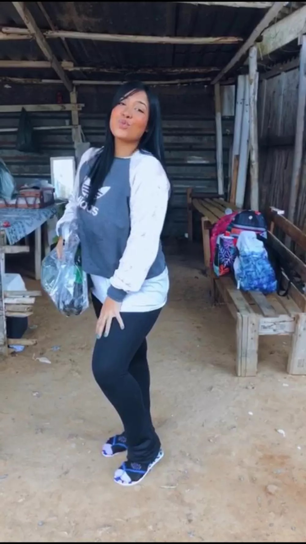 Marta Carollina aguarda visita do lado de fora do presídio (Arquivo Pessoal) Marta Carollina posa de pé em área fechada com chão de barro. Veste leggings e moletom.