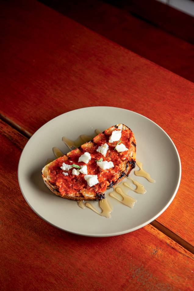 Tostada de sobrasada: embutido desfeito sobre fatia de pão levemente tostada, queijo feta e mel Tostada de sobrasada: embutido desfeito sobre fatia de pão levemente tostada, queijo feta e mel