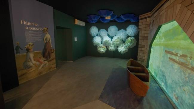 renoir Exposição com projeção de imagens a fundo e réplica de barco à direita