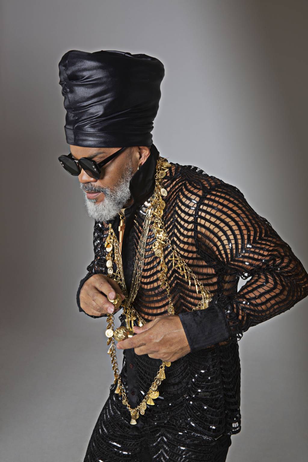 CARLINHOS BROWN (Fernando Torquatto-Divulgação) Carlinhos Brown posa de óculos de sol, turbante e roupa preta e dourada.