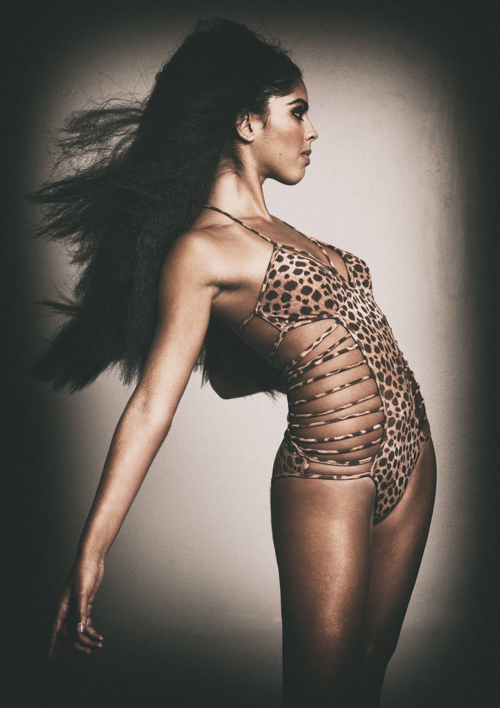 ISABELA GIL (Fernando Torquatto-Divulgação) Isabela Gil posa olhando para o lado com o corpo arqueado e os braços para trás. Os cabelos aparecem ao vento. Ela veste uma peça de maiô em oncinha.