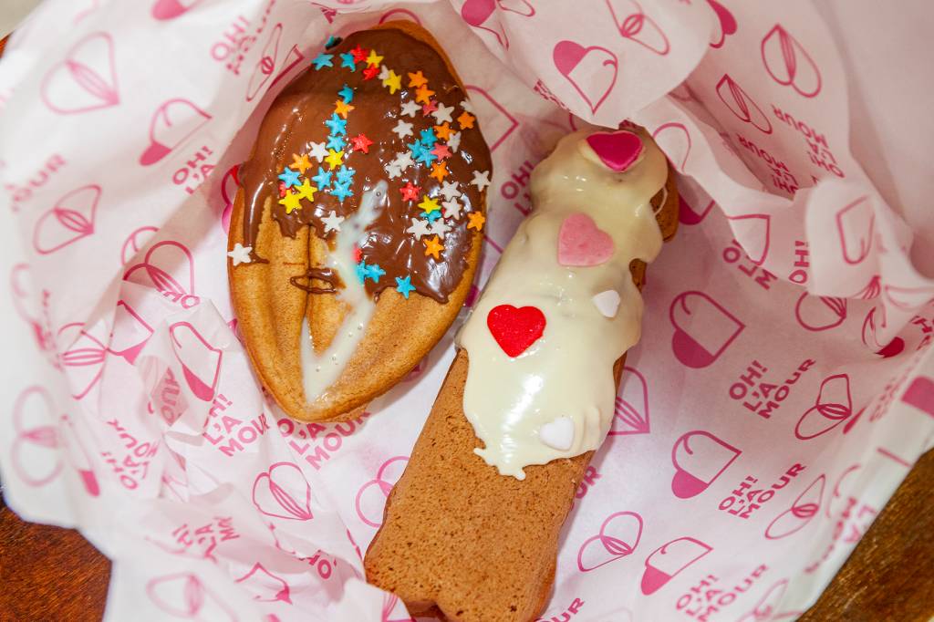 L’Amour SP (3) Waffles coloridos em forma de pênis e vagina fotografados de cima dentro de caixa branca.