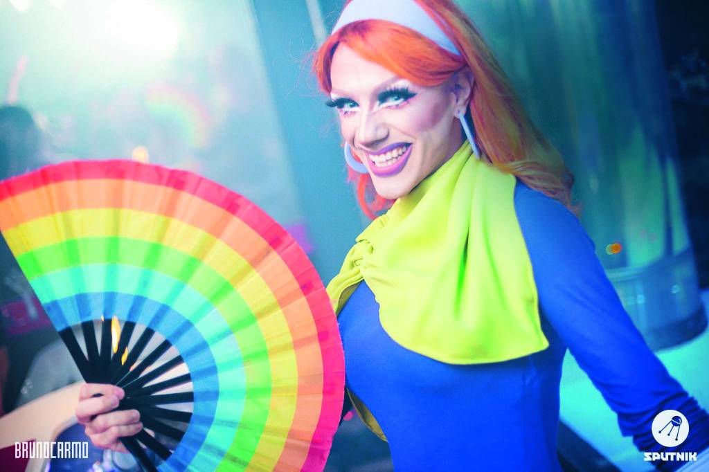 Megazord – Amy Candy (BRUNO CARMO-DIVULGAÇÃO).jpg DJ drag queen fantasiada de Daphne com um leque colorido em uma das mãos
