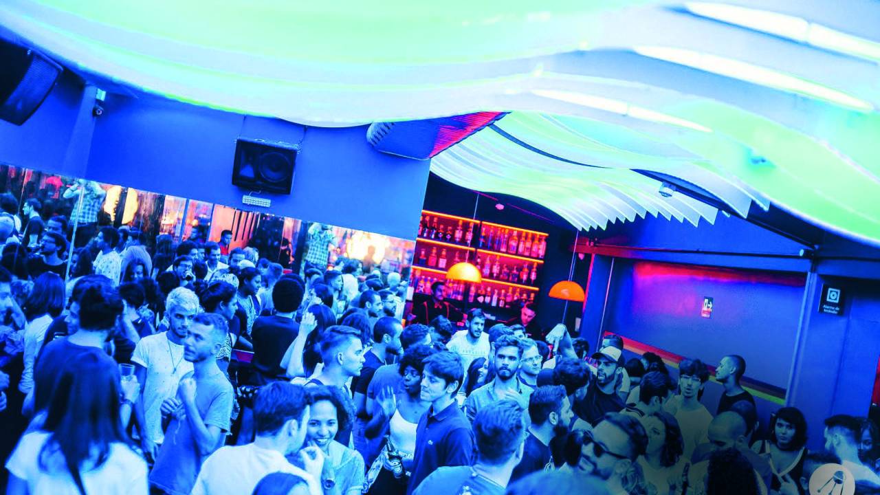 Pessoas em uma festa. Uma luz azul ilumina o ambiente da balada