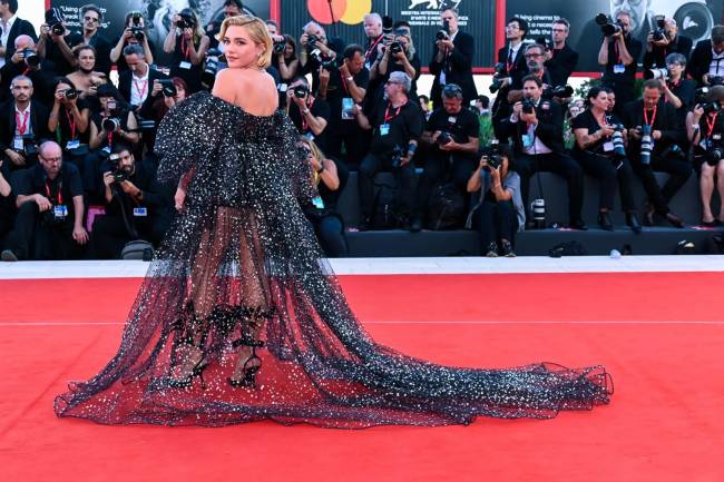 A atriz Florence Pugh no tapete vermelho do Festival de Veneza; com vestido preto brilhante