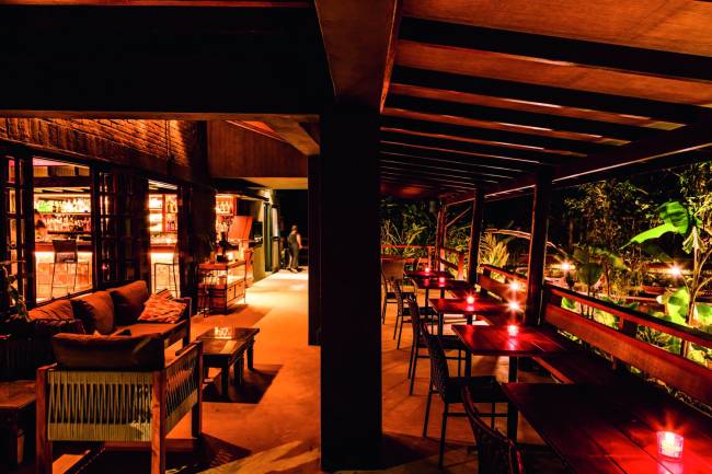 Bar do Manacá Ambiente do restaurante com mesas, teto de madeira e iluminação amarelada