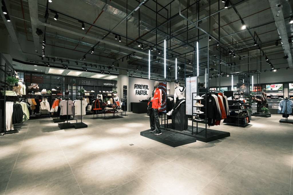 11 – Shopping Metrô Tatuapé – Puma (Divulgação) Foto exibe interior de loja da Puma com círculos de luz no chão cinza e manequins vestidos ao fundo.