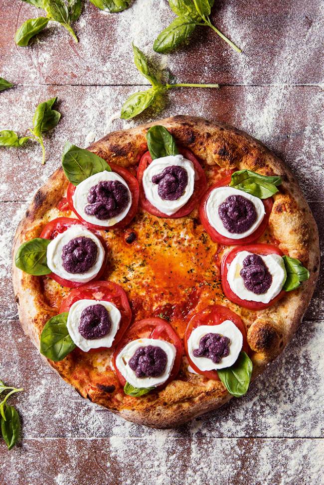 Pizza caprese Bráz com manjericão, mussarela de búfala, rodelas de tomate caqui e pesto de azeitona preta