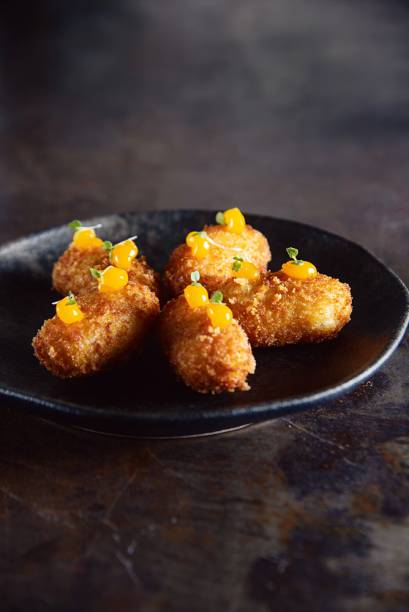 Croqueta à carbonara: molho bechamel, queijo grana padano e bacon enfeitado com manchas de gema cremosa por cima