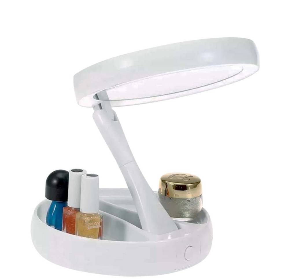 Espelho dobrável em formato redondo com porta-treco na base. Ele é branco e possui leds para ver melhor o reflexo