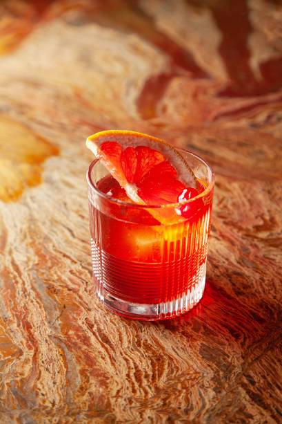 Alto negroni: gim, um toque de cachaça com infusão de nibs de cacau e laranja desidratada, Campari e vermute tinto Alto negroni: gim, um toque de cachaça com infusão de nibs de cacau e laranja desidratada, Campari e vermute tinto