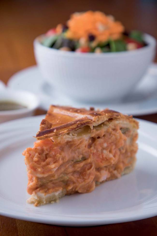 Fatia de torta salgada sobre prato branco de porcelana