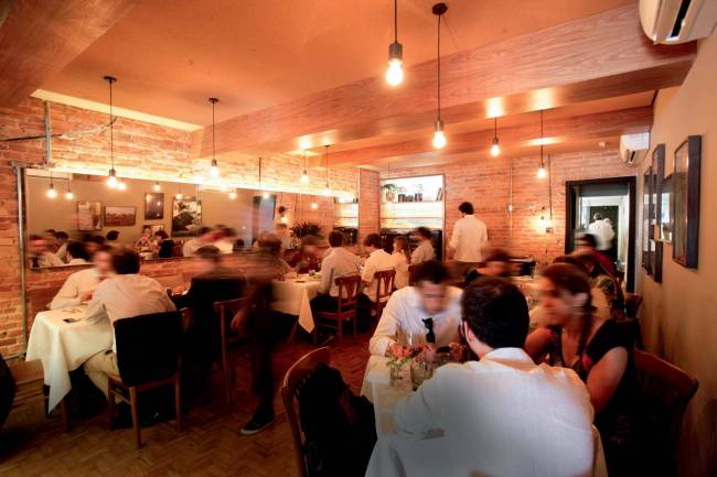 Ambiente interno de restaurante com pessoas em mesas e andando