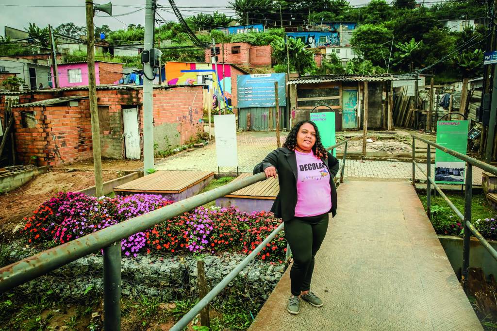Favela dos Sonhos Imagem mostra mulher apoiada em corrimão, com comunidade ao fundo