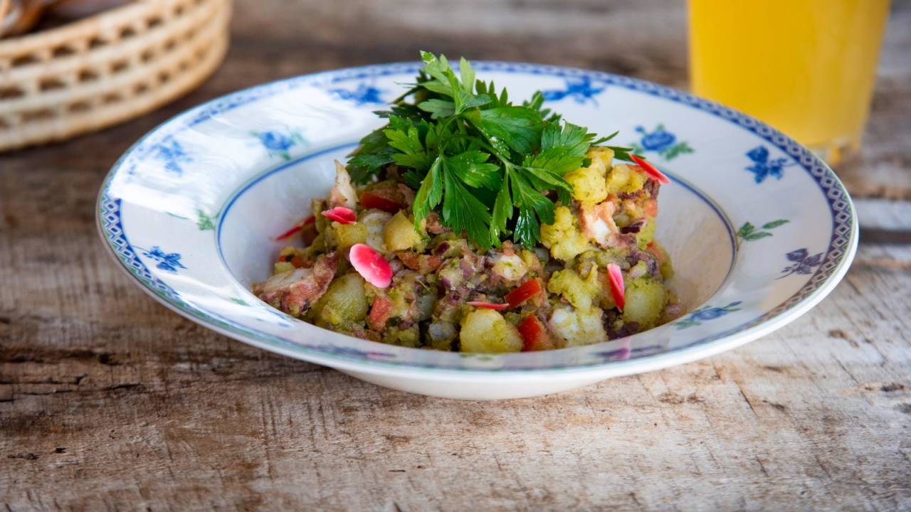 Prato fundo de louça branca e azul com frutos do mar picados cobertos por salsinha.