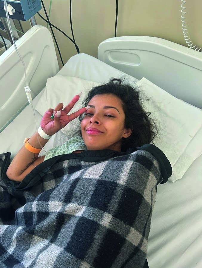 Amanda Santos Silva – Caso meningite Grande SP (Arquivo Pessoal) (4) Moça negra faz sinal de dois com uma das mãos, deitada com soro na veia e coberta por cobertor quadriculado.