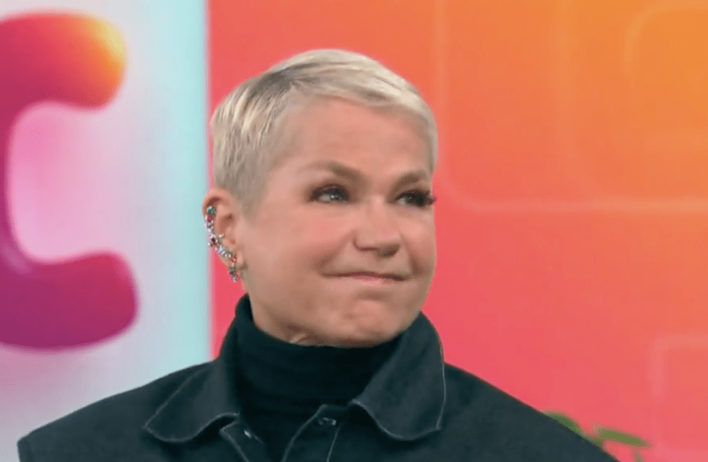 Xuxa no Mais Você vestindo uma blusa preta de gola alta e uma jaqueta escura