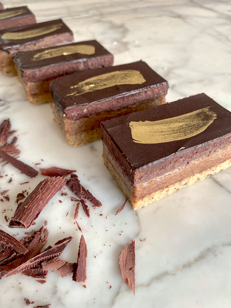 Doces saudáveis – Fioca – Regina Paula Linha com unidades de doce com camadas de chocolate coberto por tintura dourada.