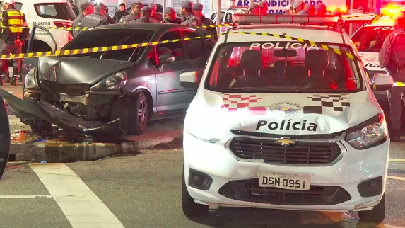 um carro batido, uma viatura e vários policiais atrás