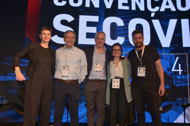 Marianne Wenzel, José Armênio, Mauro Teixeira, Vivian Barbour e Marcelo Falcão Imagem mostra cinco pessoas reunidas em palco. Na parte de trás, pode-se ler em telão: Convenção Secovi